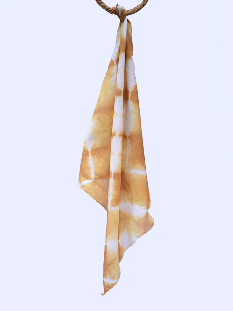 A vibrant tie-dye scarf elegantly draped against a clean white wall, showcasing its colorful patterns.