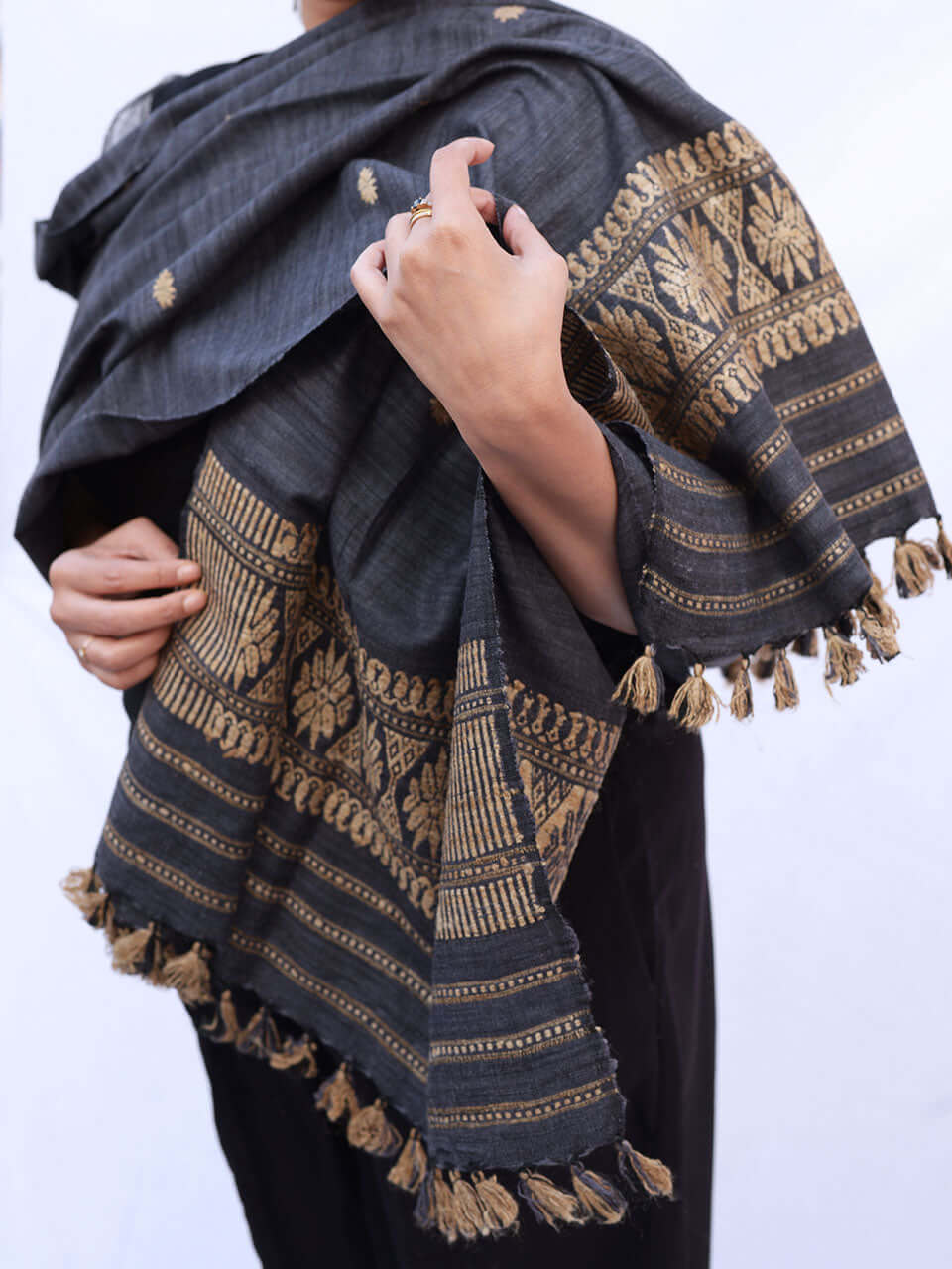 A woman elegantly draped in a grey-colored scarf, showcasing a warm and stylish accessory