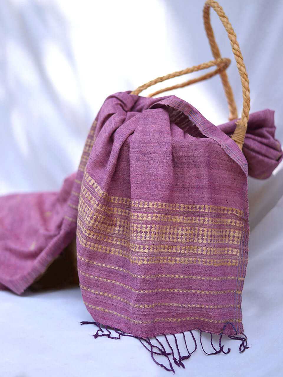 A wicker basket and a purple scarf are elegantly arranged on a white table, creating a serene and inviting atmosphere.