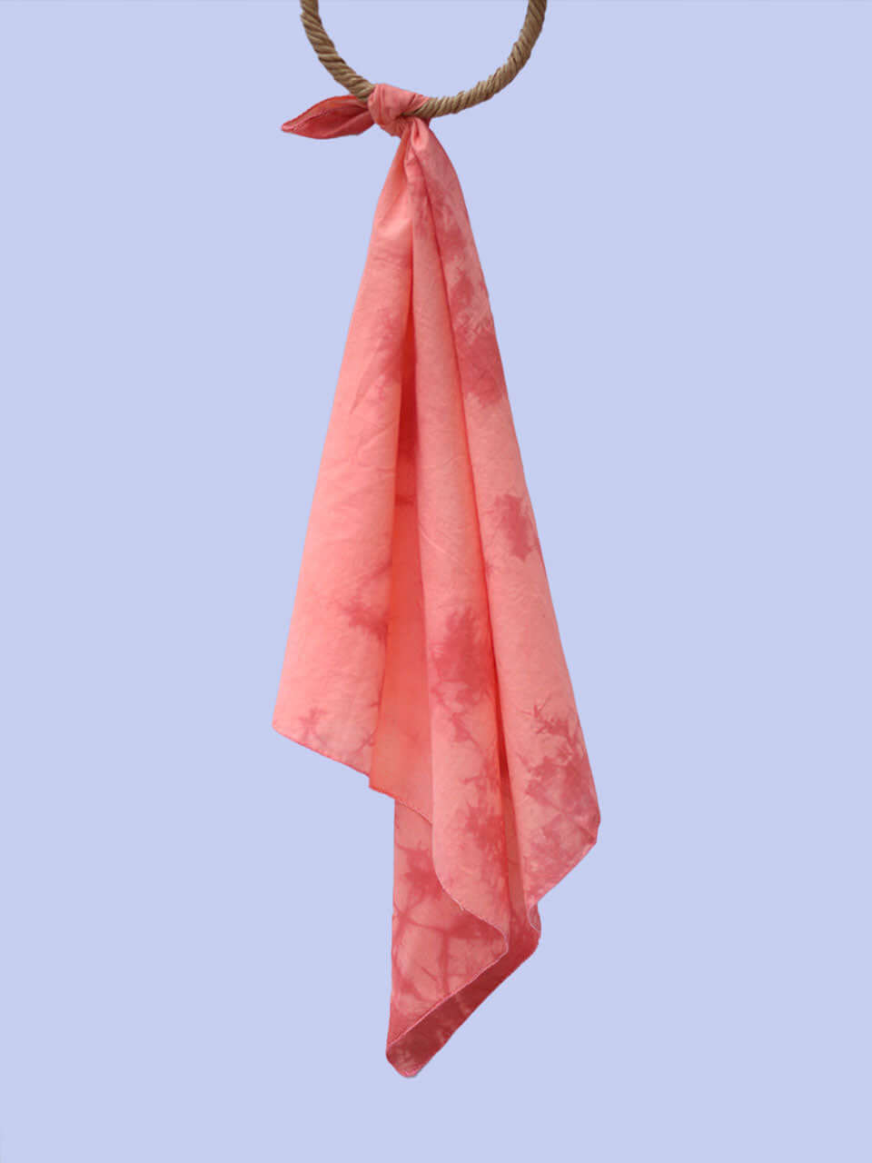 A vibrant tie-dye scarf elegantly draped against a clean white wall, showcasing its colorful patterns.
