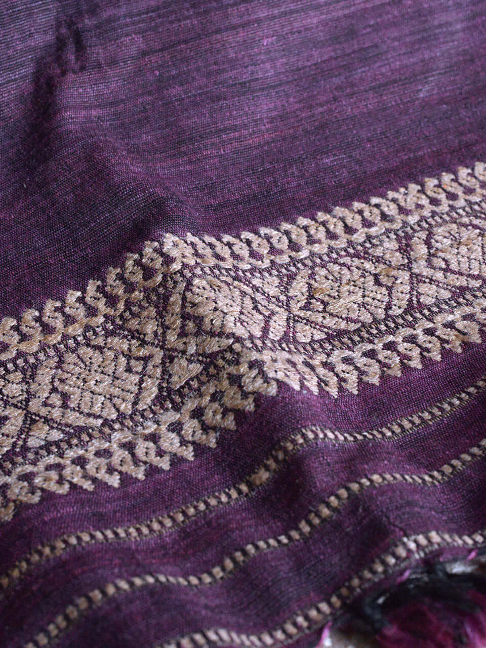 A close-up view of luxurious purple and gold fabric, showcasing intricate textures and vibrant colors