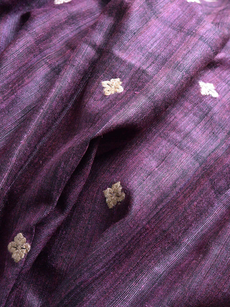 A close-up view of luxurious purple and gold fabric, showcasing intricate textures and vibrant colors
