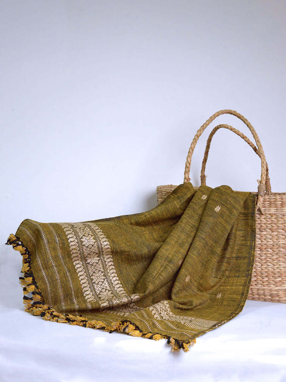 A wicker basket and a green scarf are elegantly arranged on a white table, creating a serene and inviting atmosphere