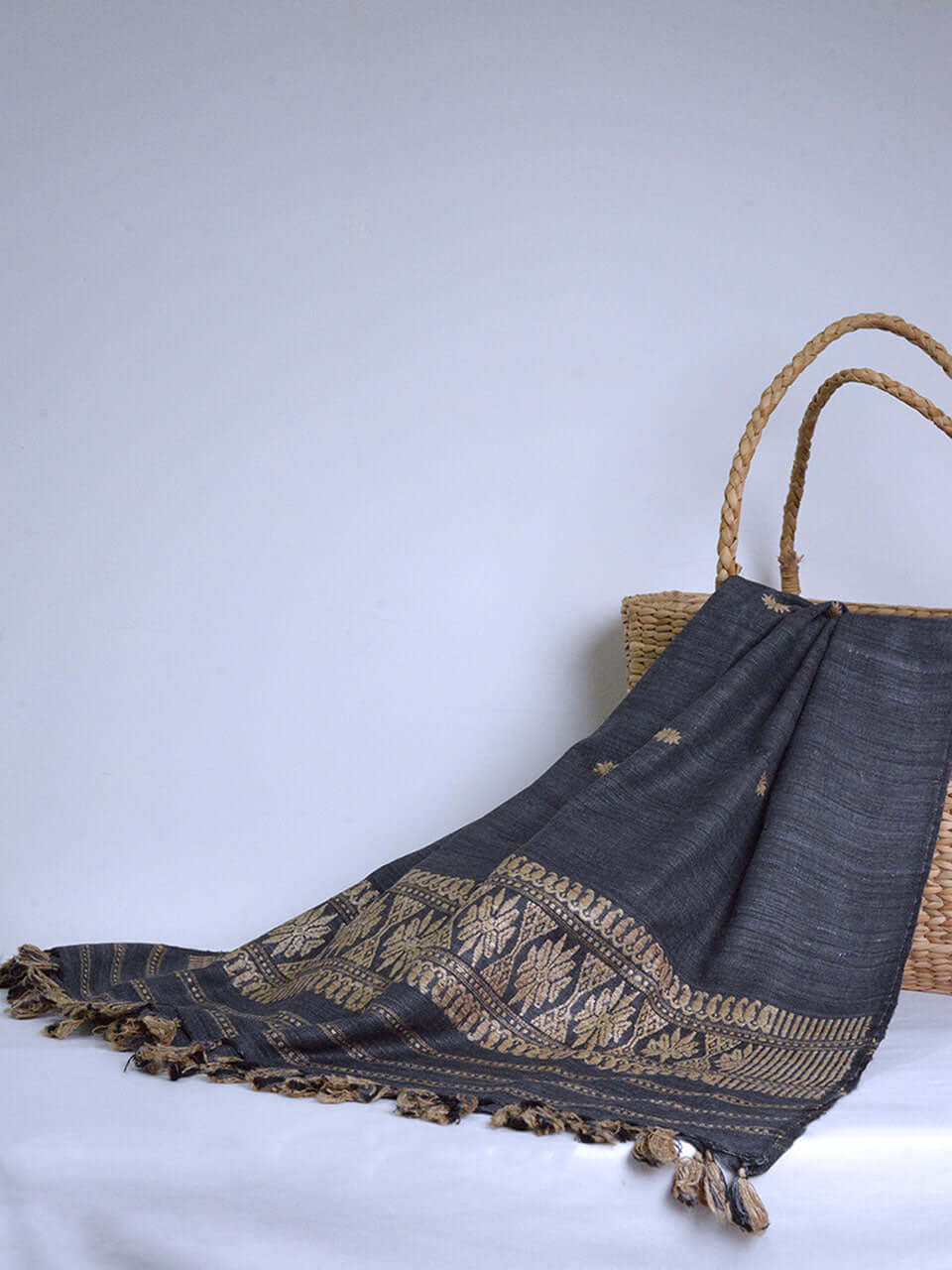 A wicker basket and a grey scarf are elegantly arranged on a white table, creating a serene and inviting atmosphere