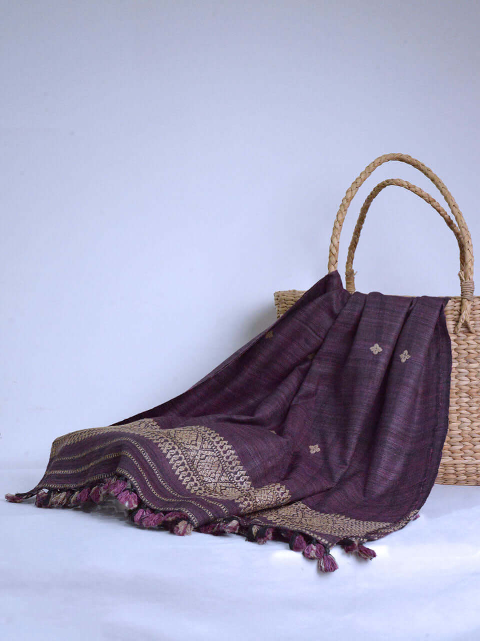 A wicker basket featuring an intricate purple and gold pattern, showcasing a blend of elegance and craftsmanship