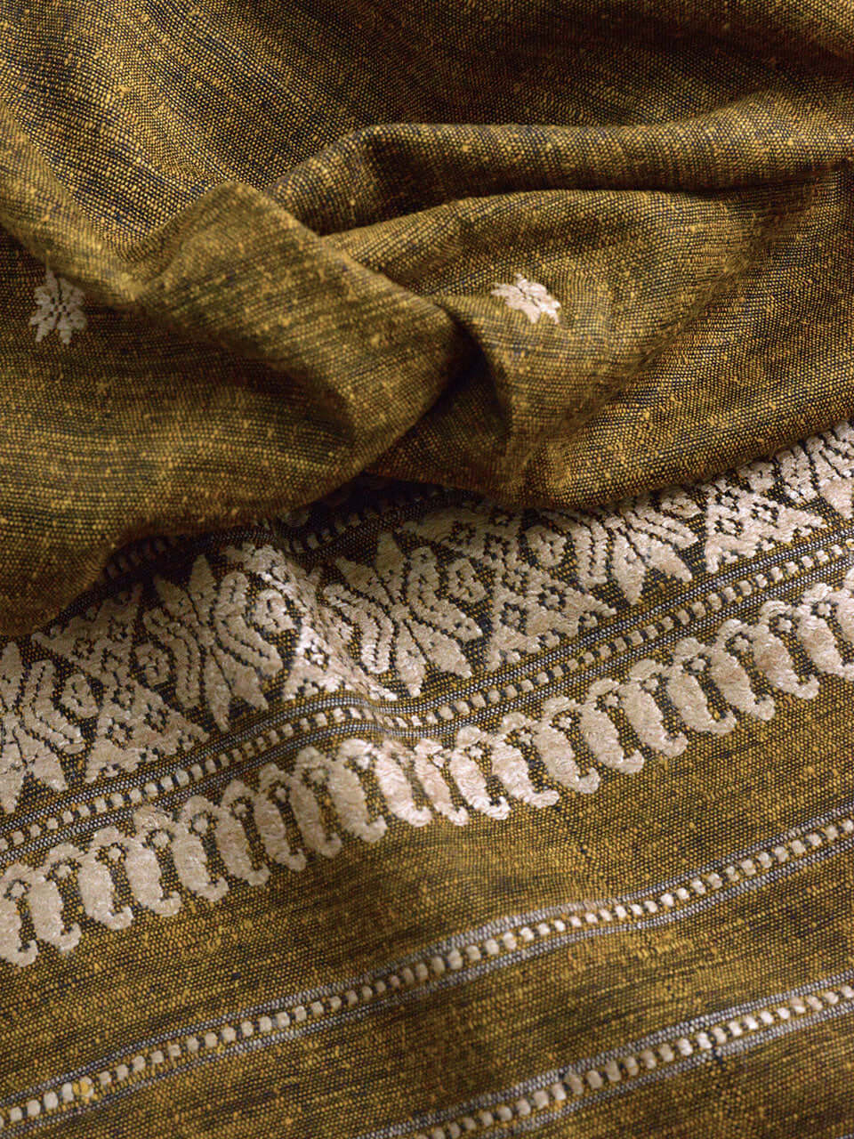 Close-up of green and white fabric featuring intricate embroidery details, showcasing texture and design