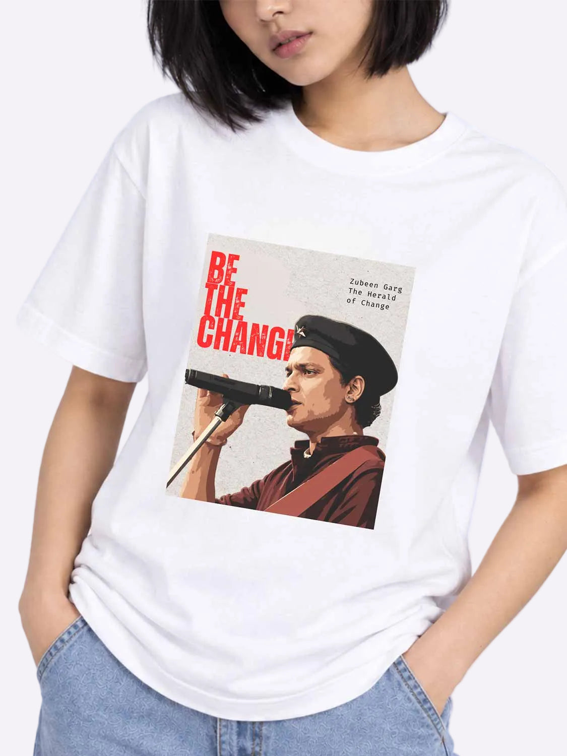 A woman wearing a white short-sleeve graphic T-shirt with a vintage-style print of a man speaking into a microphone and the text &