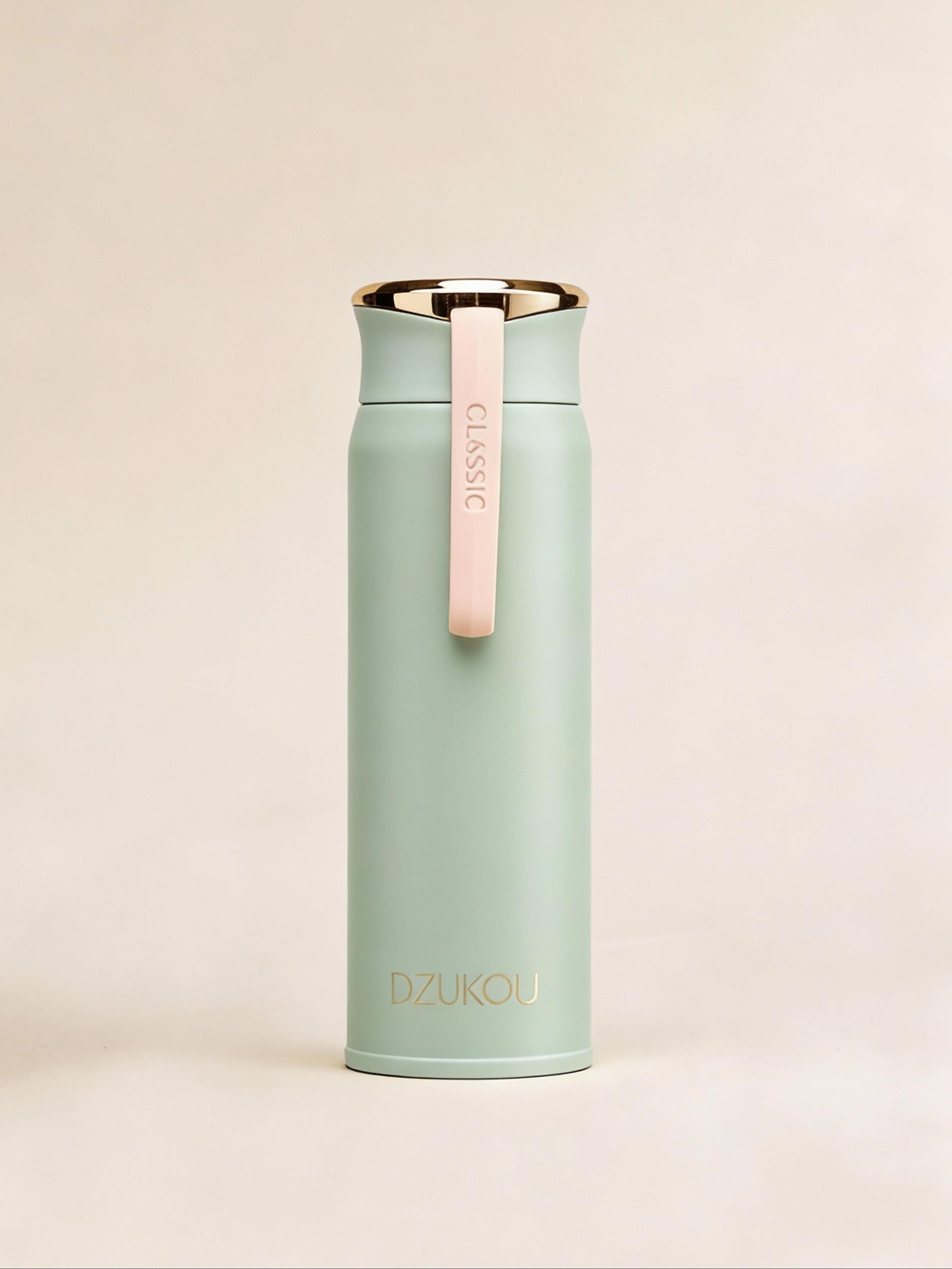 Mint green thermos with pink strap on a beige background