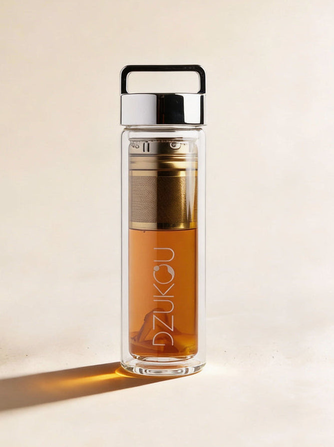 Clear glass bottle with metal cap and visible brand name on a beige background