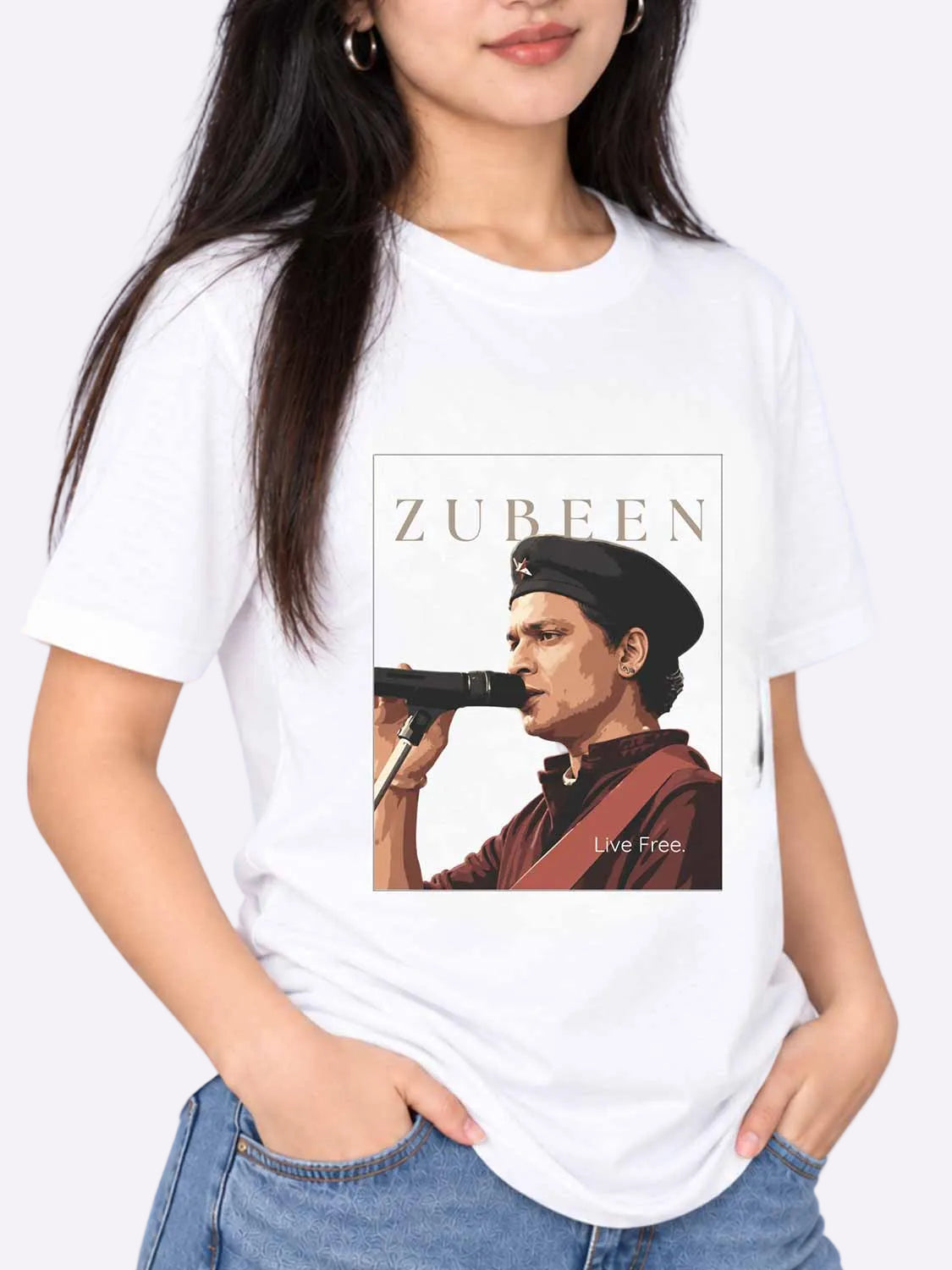 A woman wearing a white graphic t-shirt featuring a portrait of Zubeen with the text &