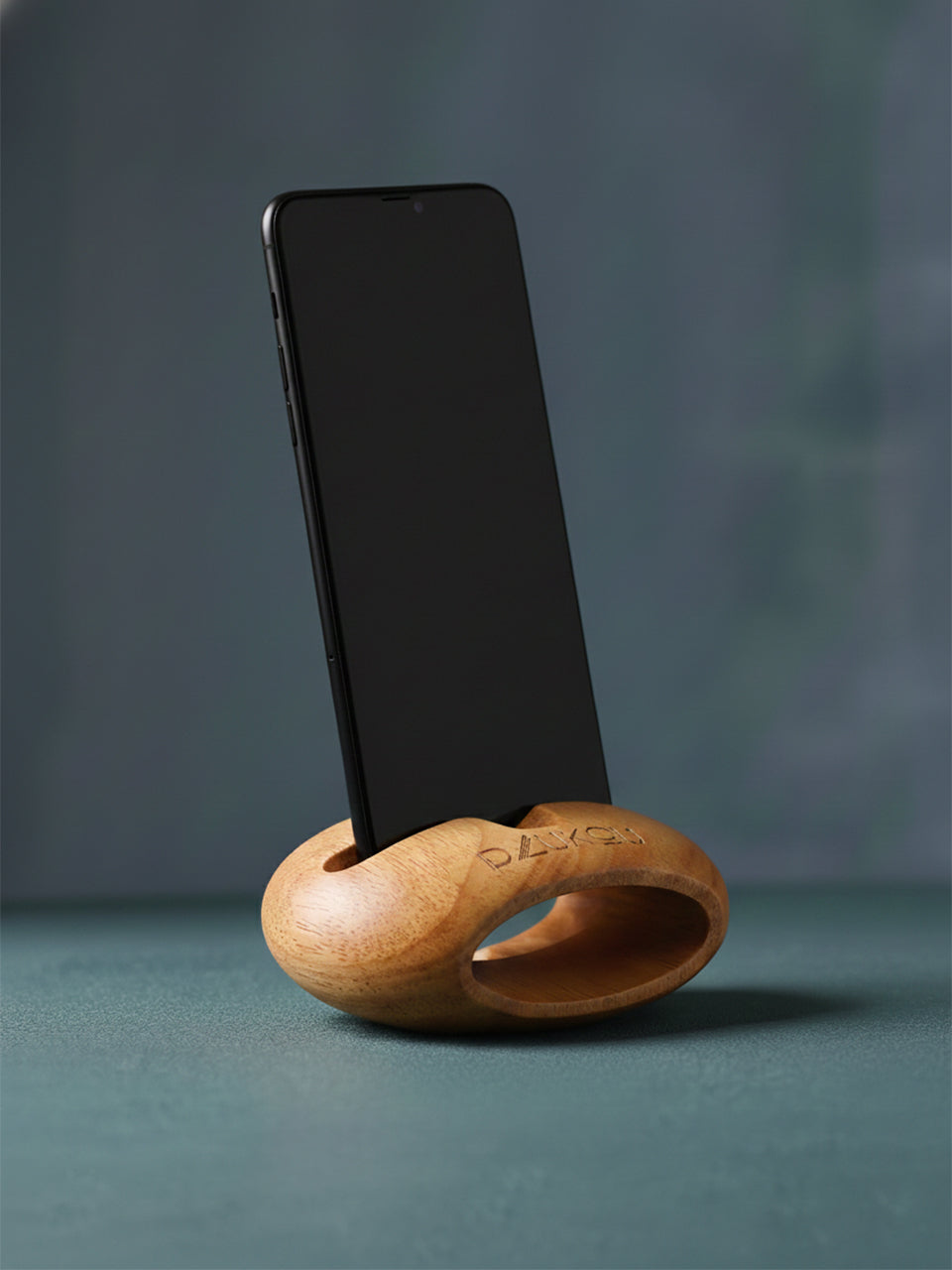 Wooden phone stand holding a smartphone on a gray background