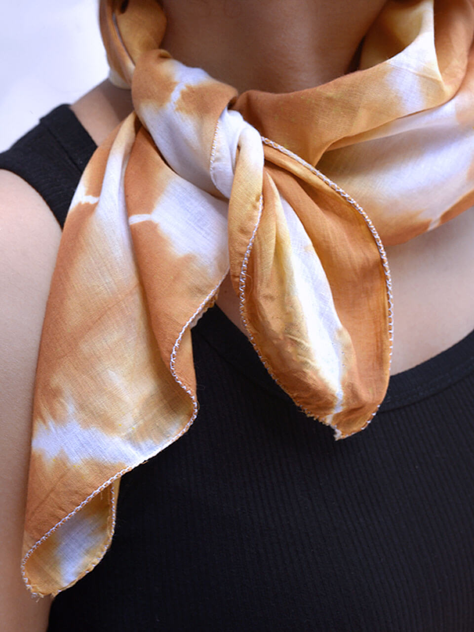 A woman elegantly wears a neck scarf featuring a stylish brown and white design.