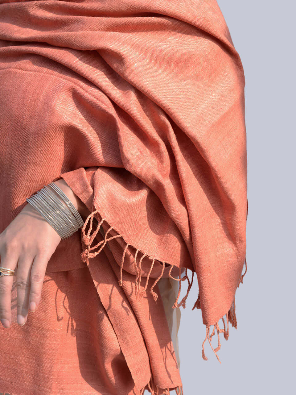 A woman draped in a soft, elegant peach stole, showcasing its smooth texture and natural color.
