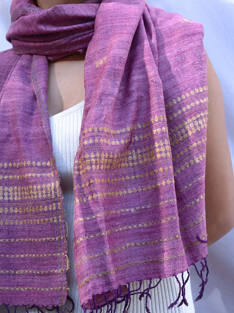 A woman elegantly draped in a purple scarf adorned with striking gold and purple stripes