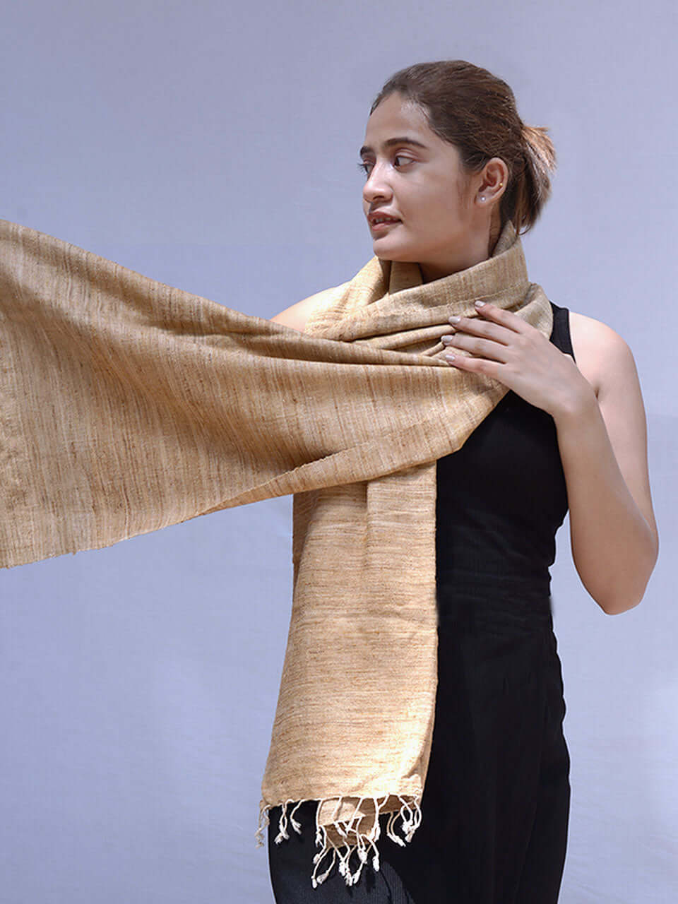 A woman in a black dress elegantly draped with a tan scarf, exuding sophistication and style