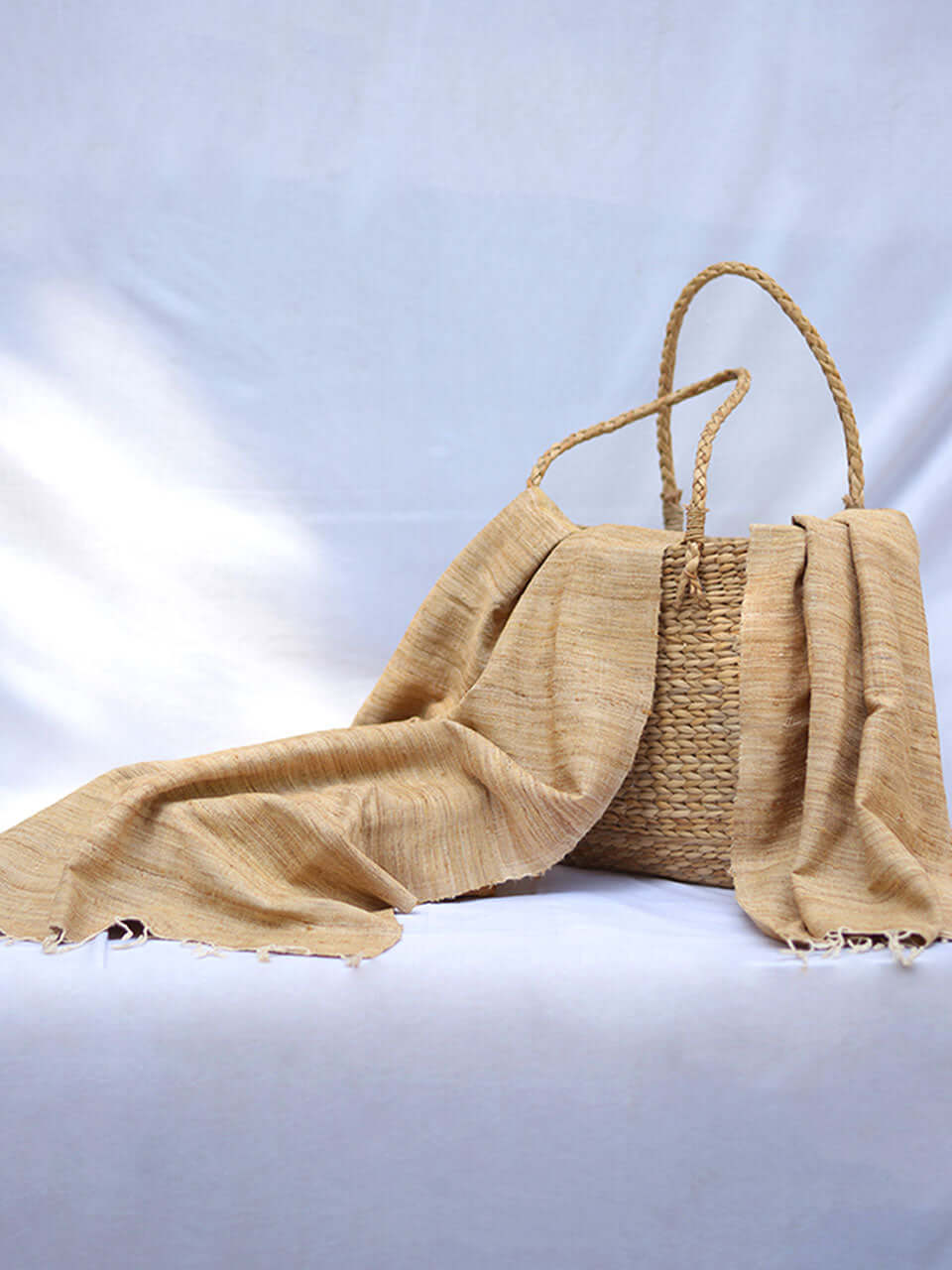 A wicker basket and a tan scarf are elegantly arranged on a white table, creating a serene and inviting atmosphere