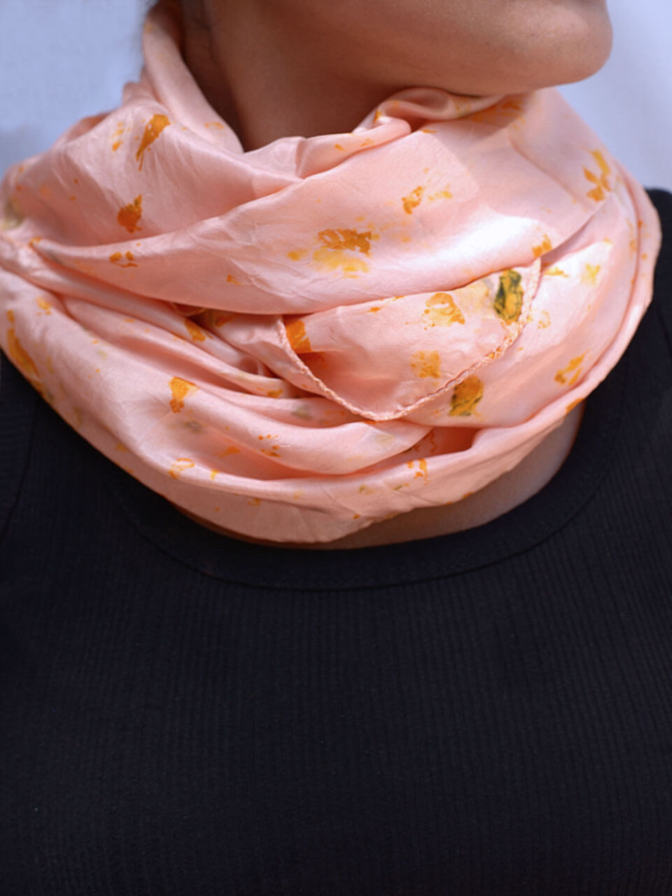 A woman adorned in a pink scarf featuring elegant gold floral patterns