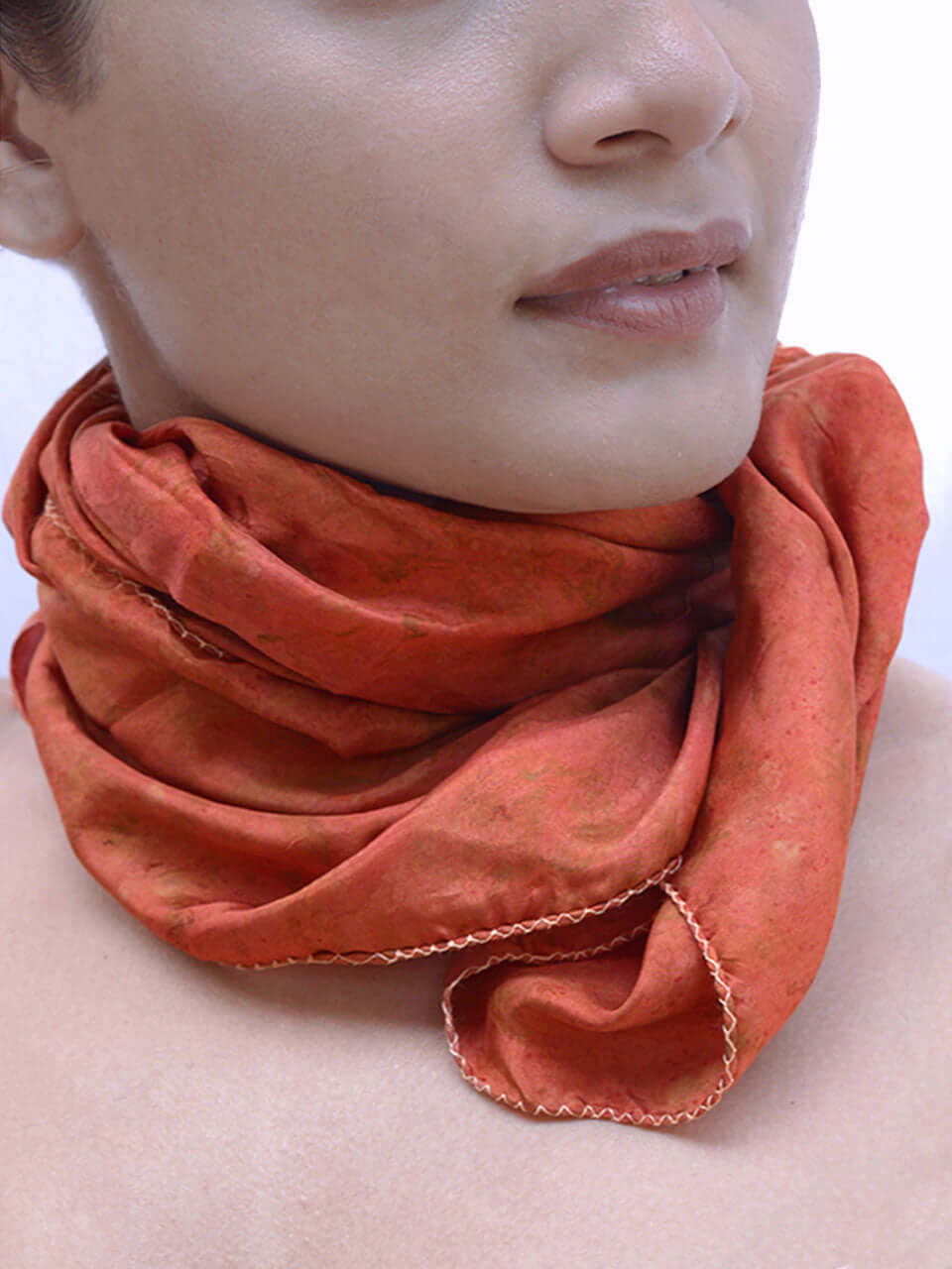 A woman elegantly adorned with a red scarf draped around her neck, exuding style and confidence