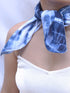 A woman elegantly draped in a blue tie-dye scarf, showcasing vibrant patterns and a stylish appearance.