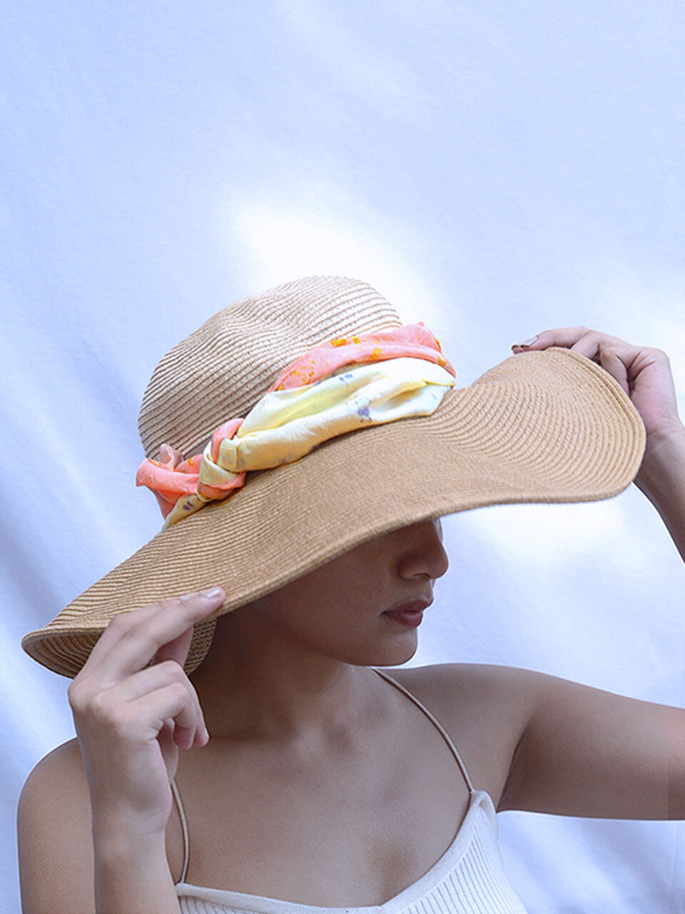 A woman wearing a stylish hat adorned with a scarf, showcasing a fashionable and elegant look