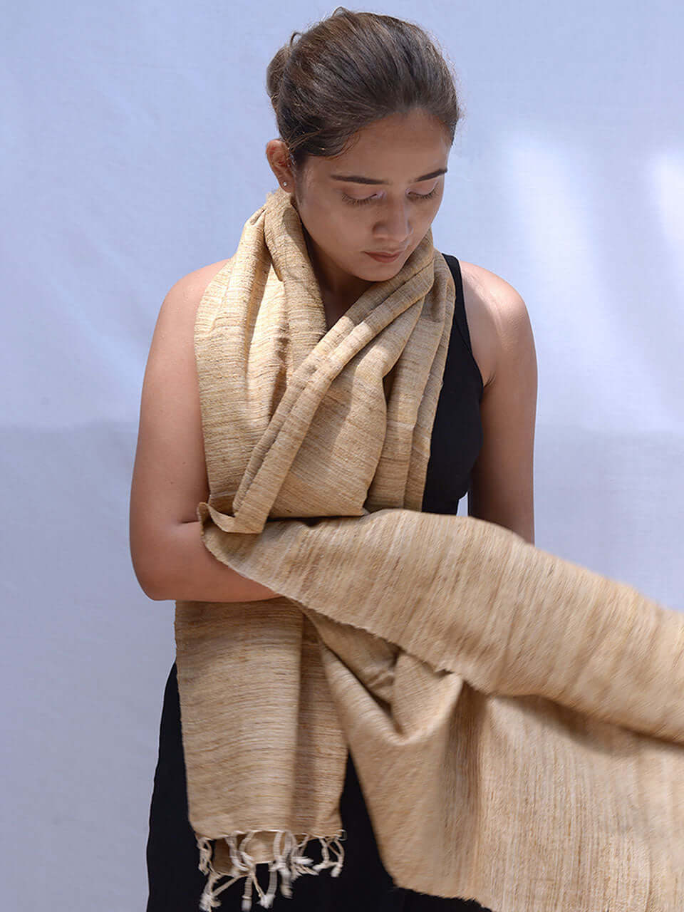 A woman in a black dress elegantly draped with a tan scarf, exuding sophistication and style