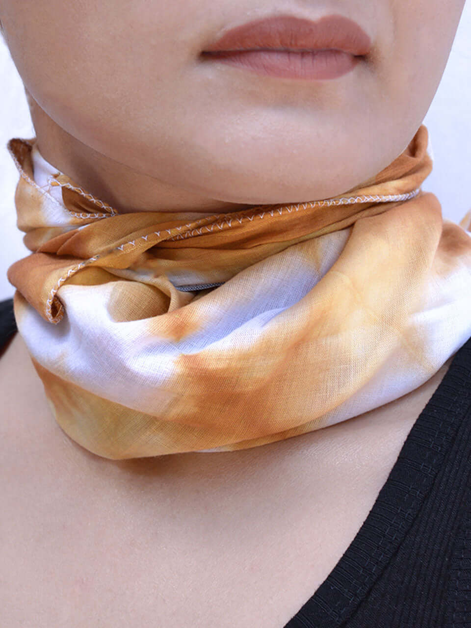 A woman elegantly wears a neck scarf featuring a stylish brown and white design.