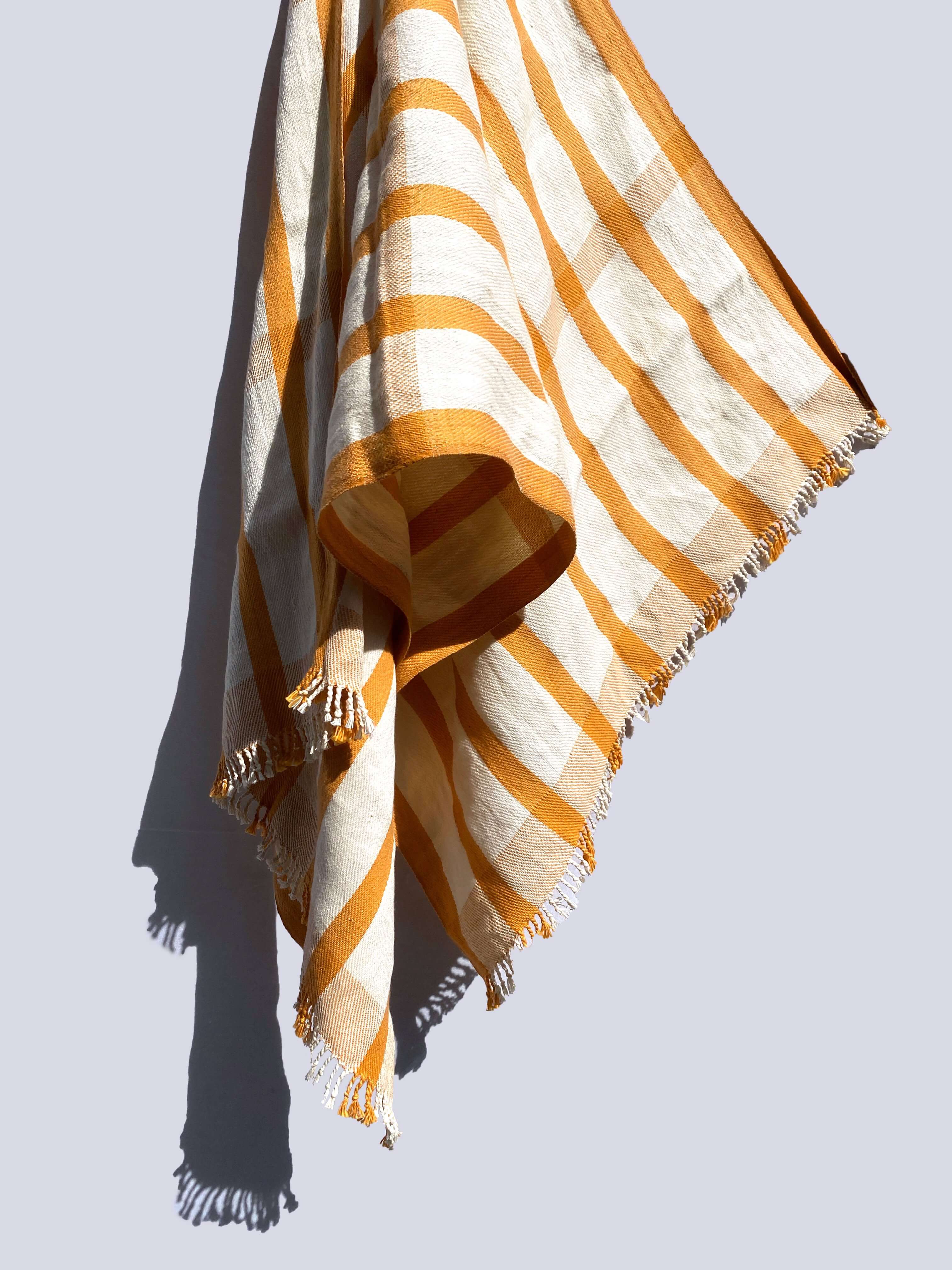A yellow and white striped organic cotton bath towel elegantly displayed on a wall.