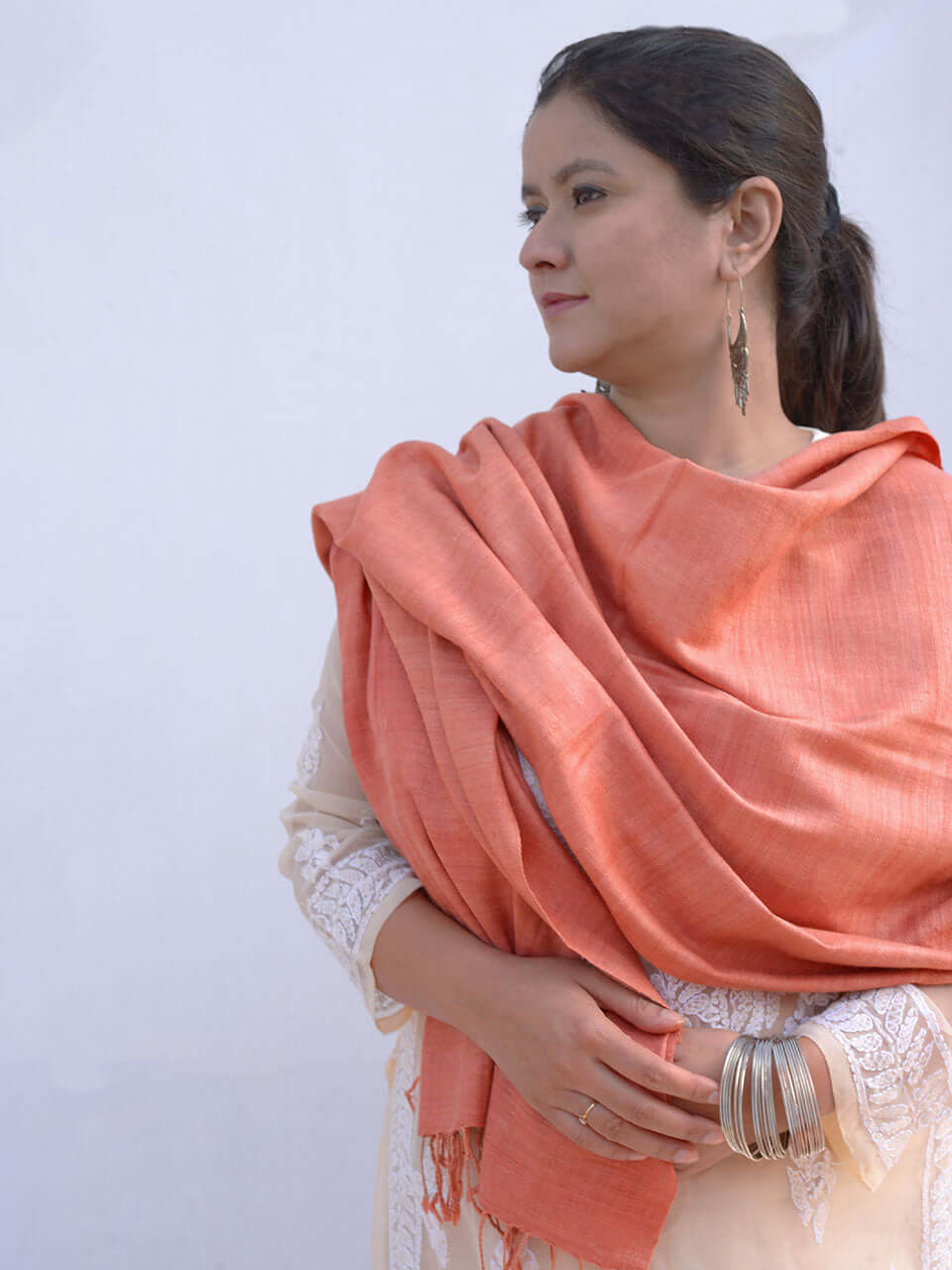 A woman draped in a soft, elegant peach stole, showcasing its smooth texture and natural color.