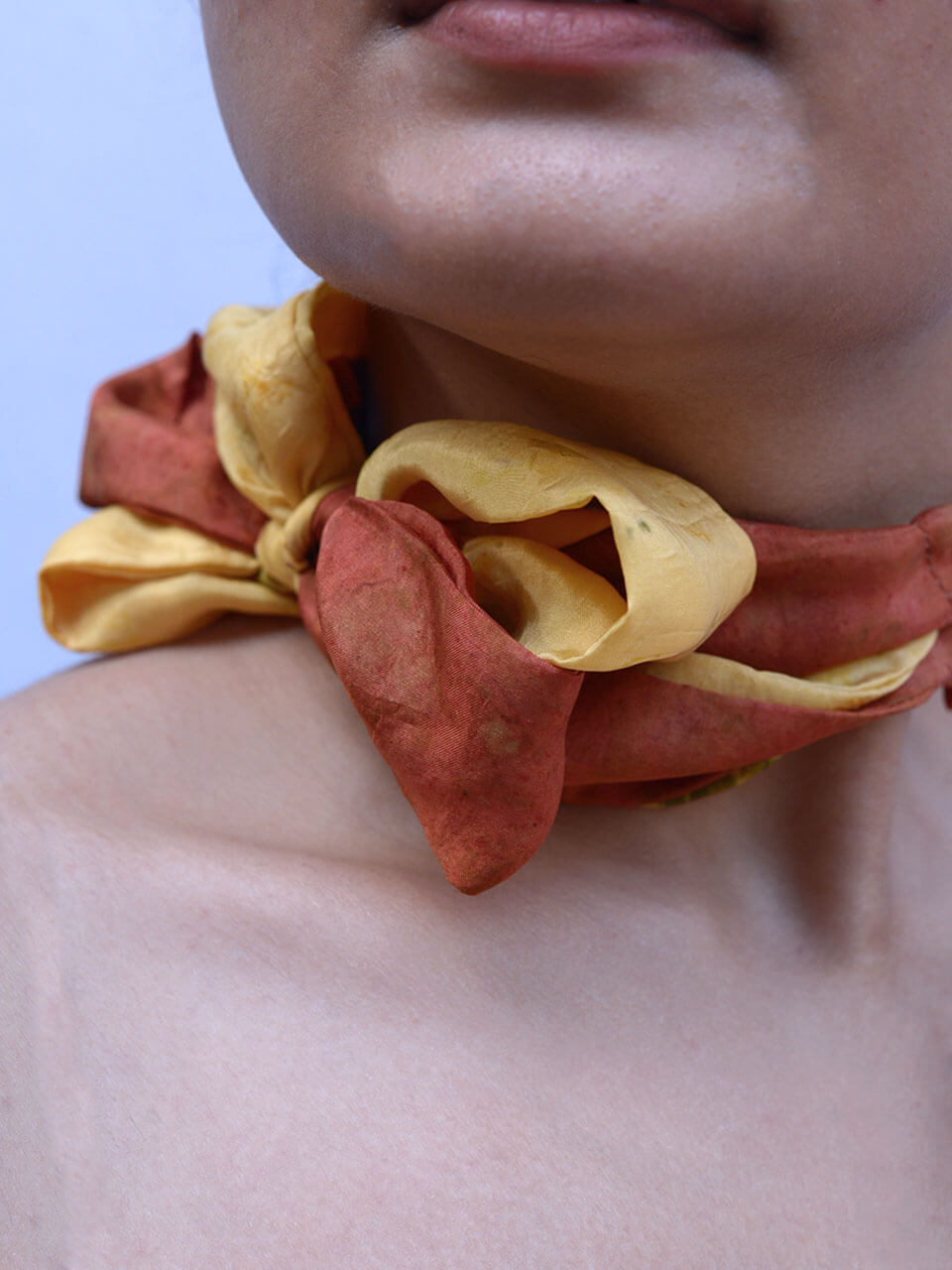 A woman elegantly draped in a vibrant red and yellow scarf, showcasing a blend of colors and style