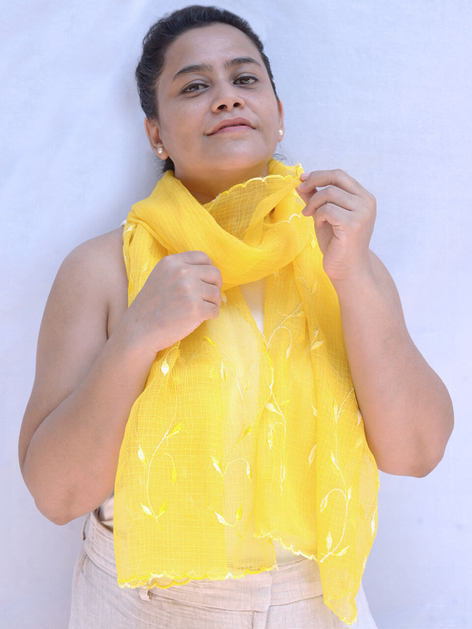 A woman elegantly draped in a vibrant yellow scarf, exuding warmth and style.