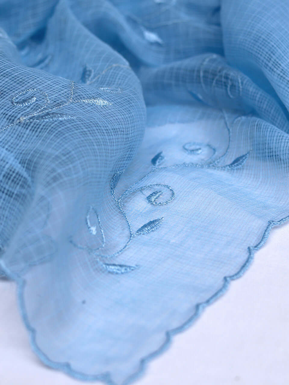 Blue fabric adorned with intricate white embroidery, showcasing a delicate and elegant design.