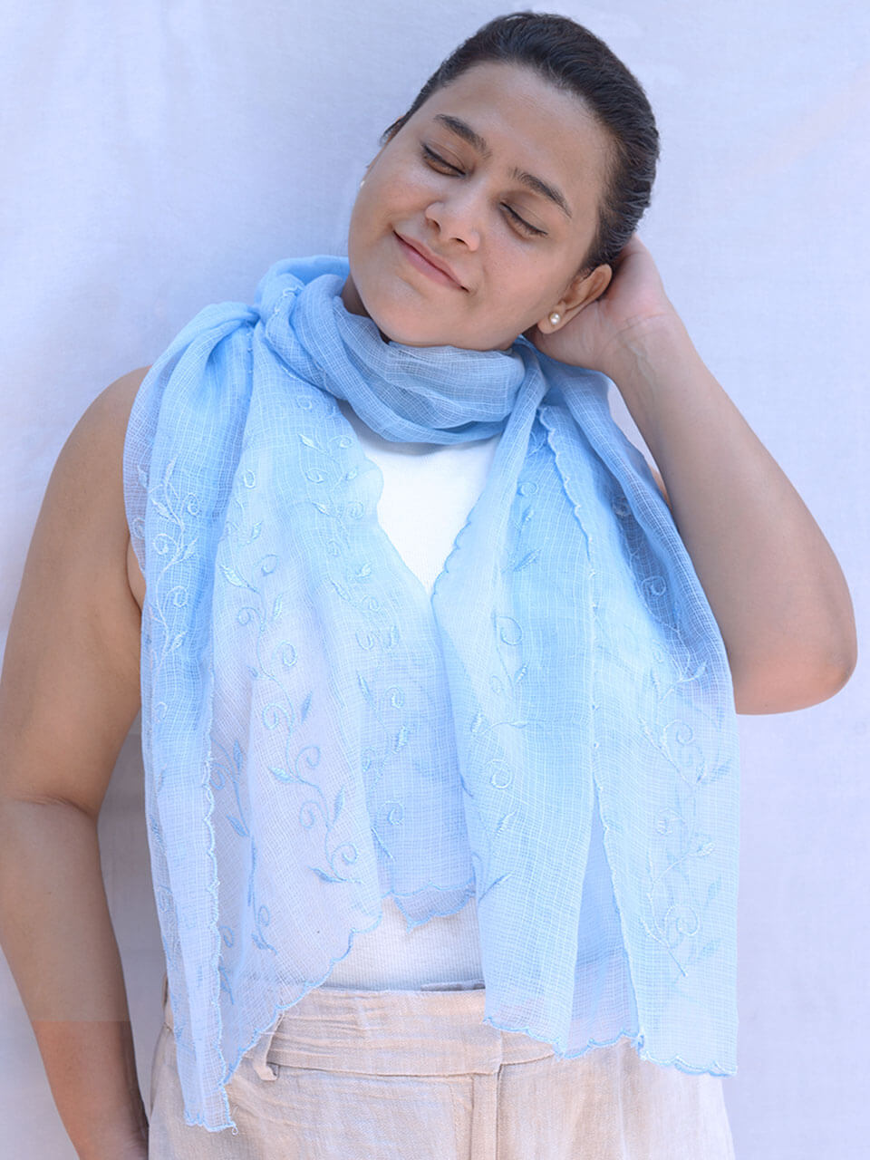 A woman elegantly draped in a light blue scarf, exuding grace and style.