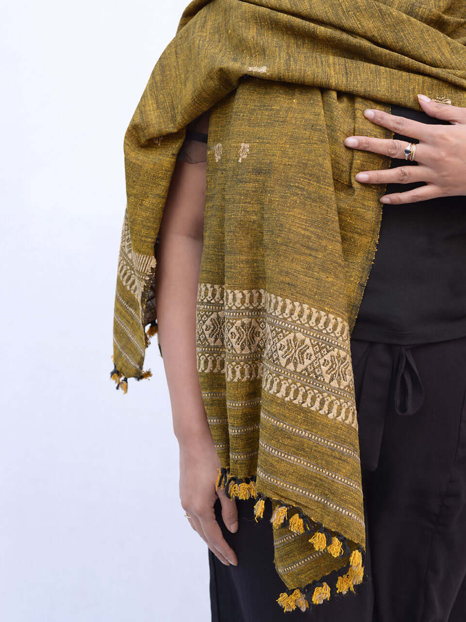 A woman elegantly draped in a mustard-colored scarf, showcasing a warm and stylish accessory