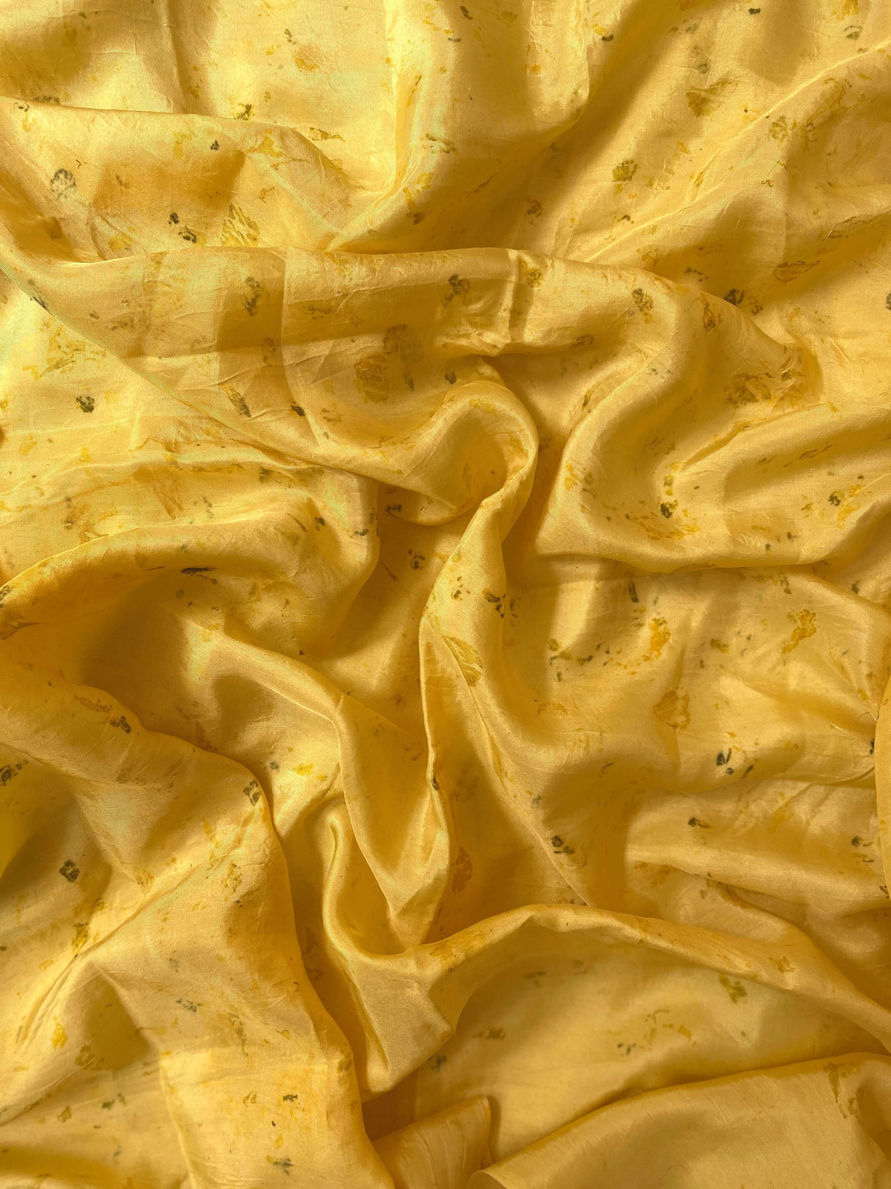 A vibrant yellow silk scarf draped elegantly, showcasing its luxurious texture and rich color