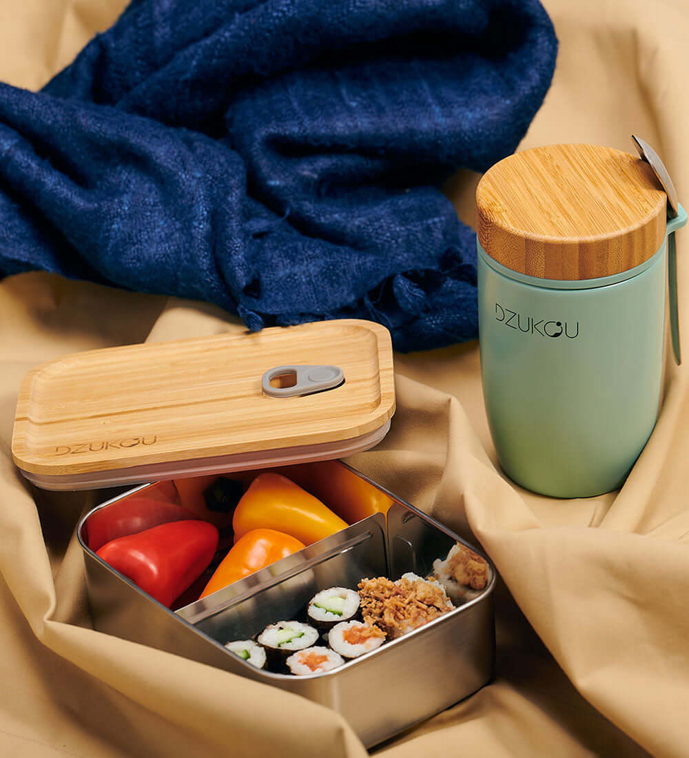 tiffin box filled with sushi and veggies kept near a bottle
