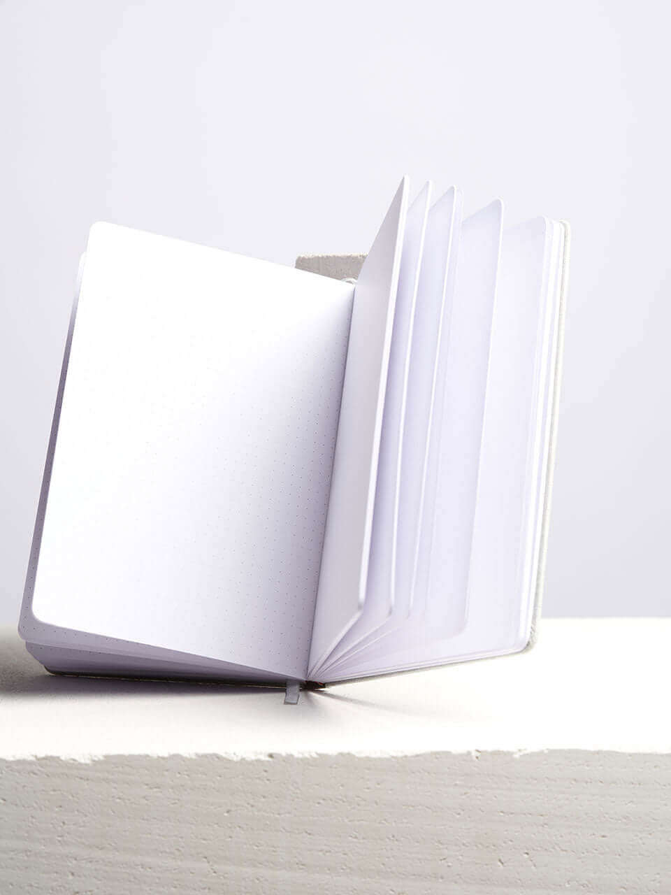A blank notebook place beside a white block with a clean white background.