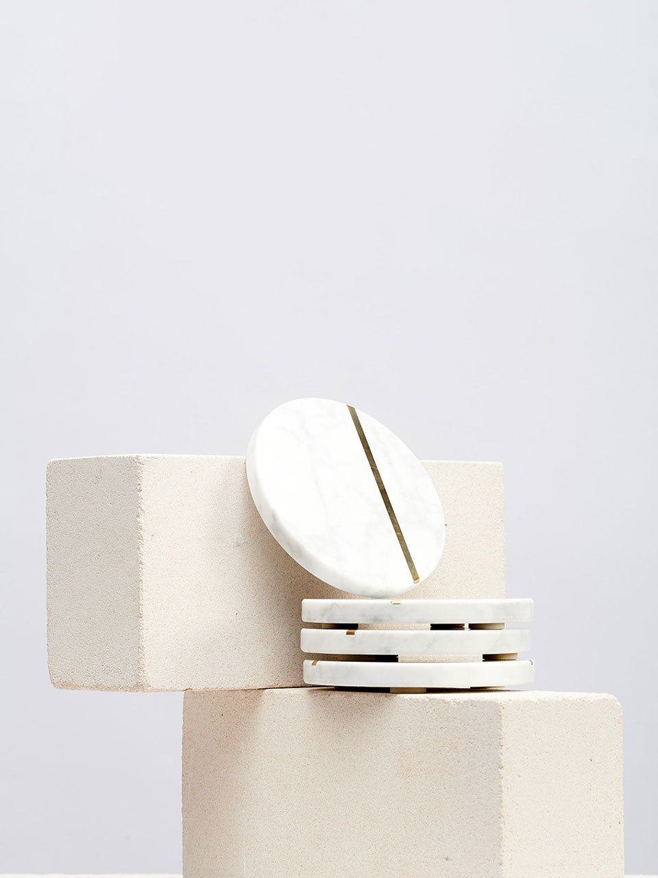 A stack of white marble coasters resting elegantly on a smooth white block.