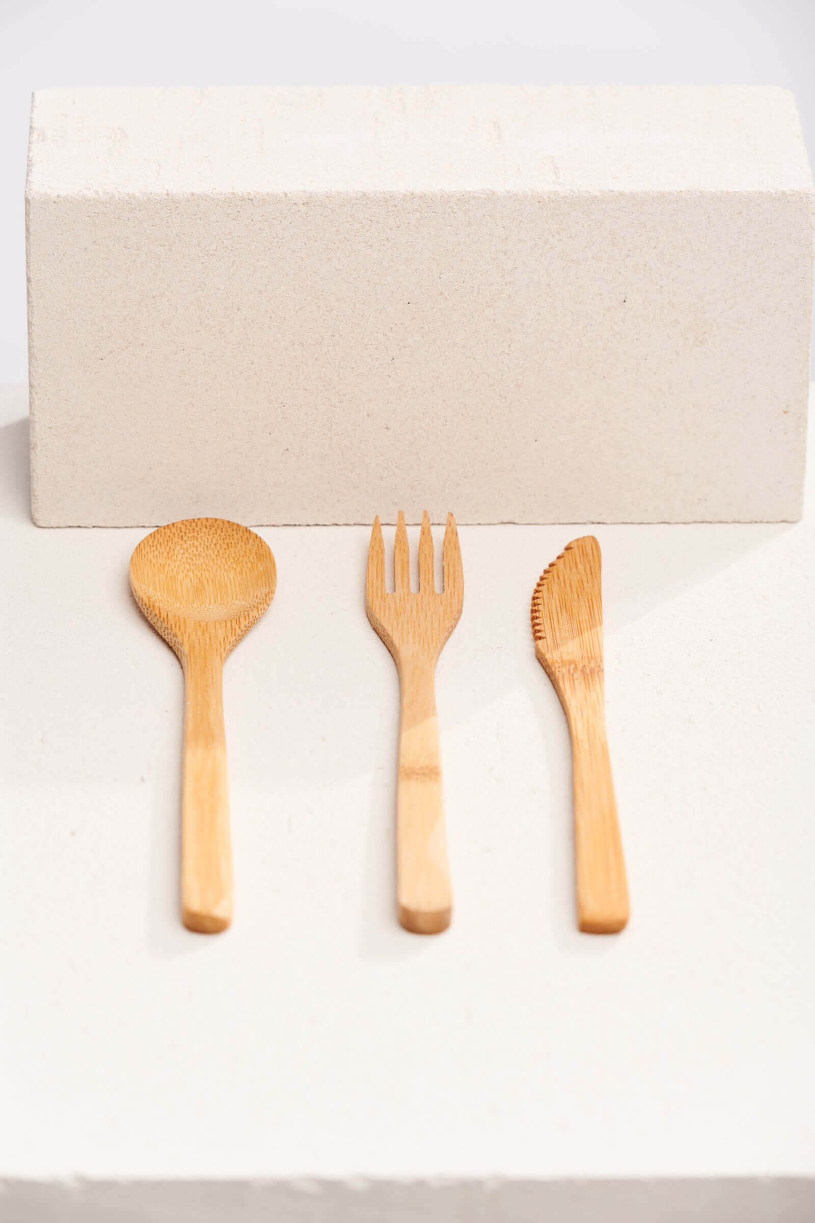 A set of three wooden spoons and forks arranged neatly on a light background