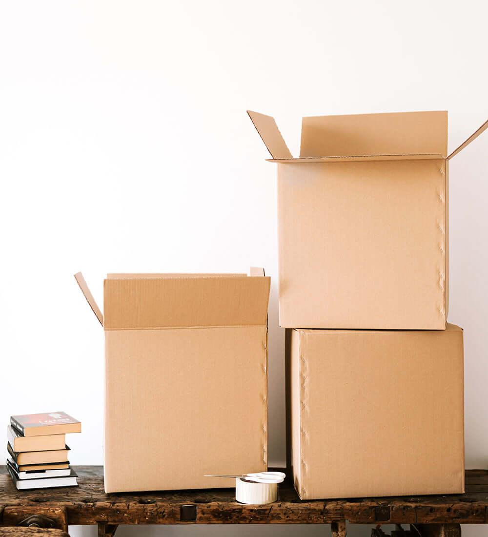 cardboard boxes, books, scissors and tape kept on a table