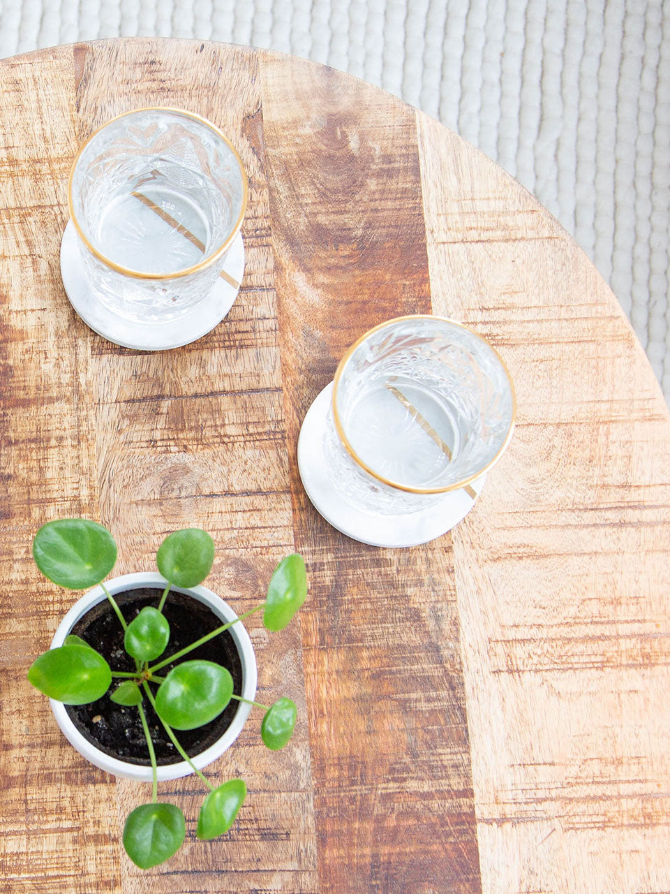 White marble coasters featuring elegant gold trim on top of a wooden table, adding a touch of sophistication to any table setting.