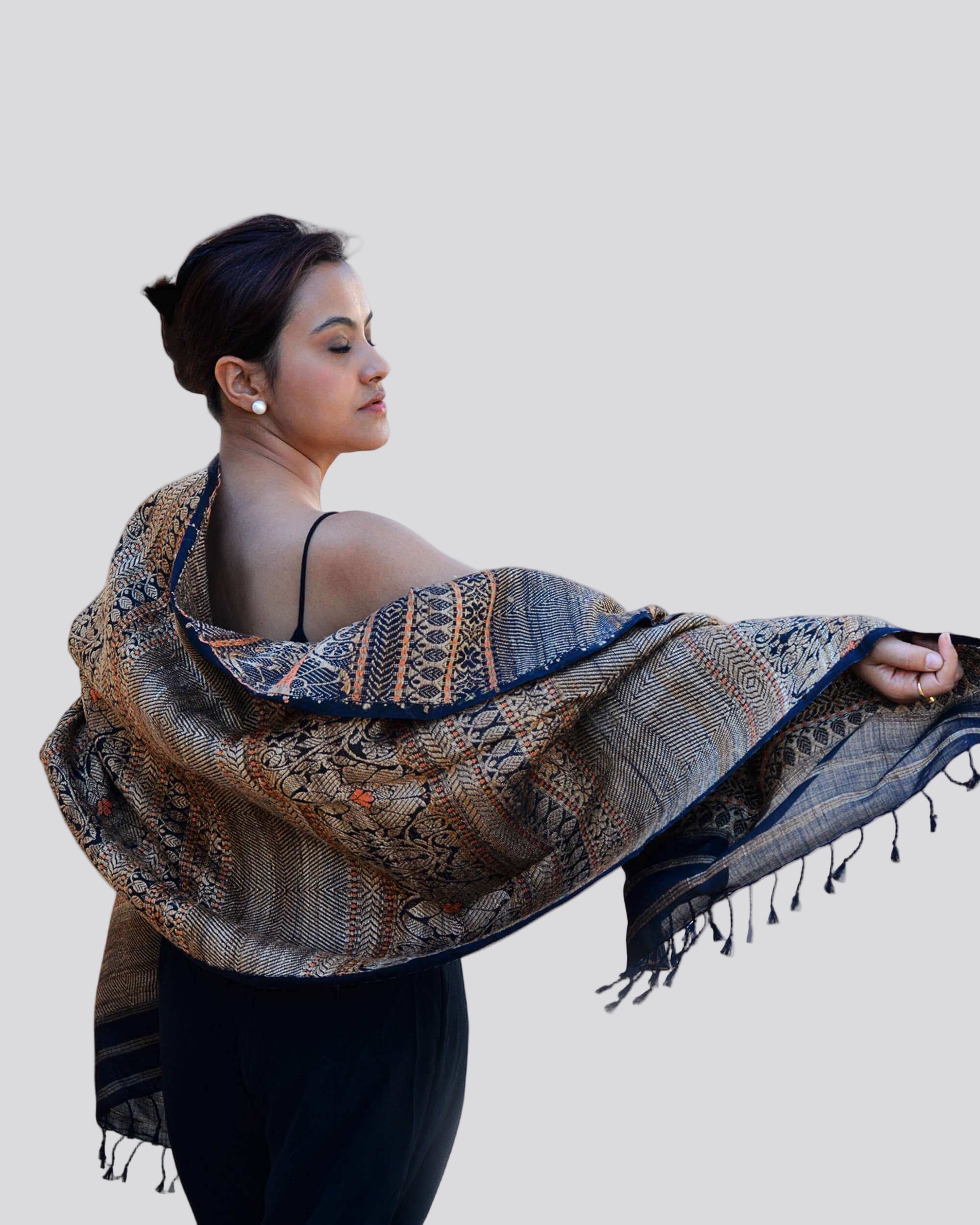 A woman elegantly draped in a patterned shawl, showcasing intricate designs and vibrant colors.