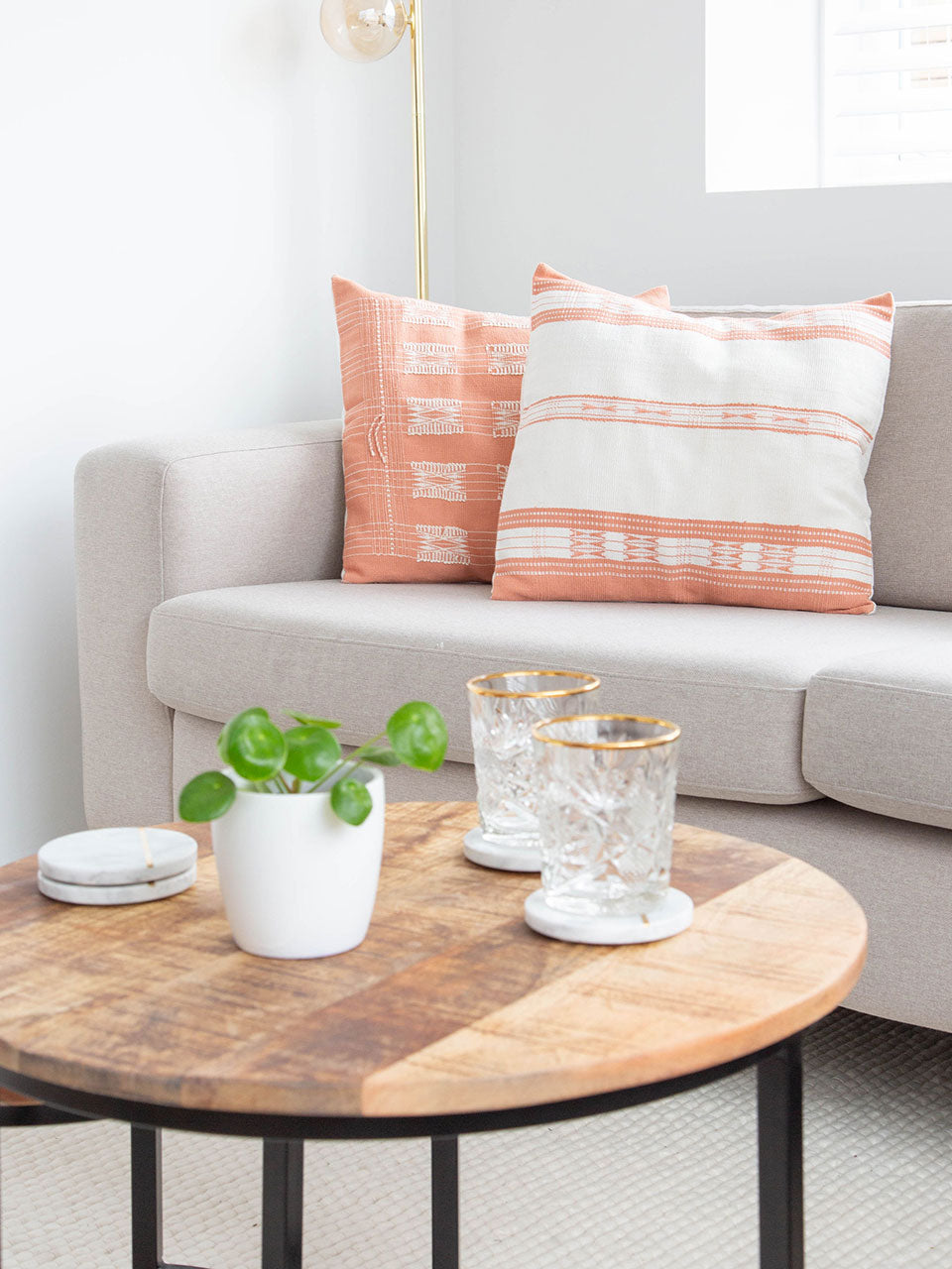 A cozy living room featuring a comfortable couch with white and pink pillow covers, a stylish coffee table, and a dining table for gatherings.