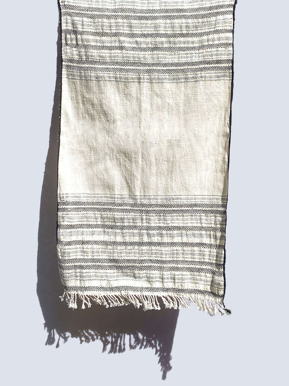 A black and white striped organic cotton hand towel elegantly displayed on a wall.