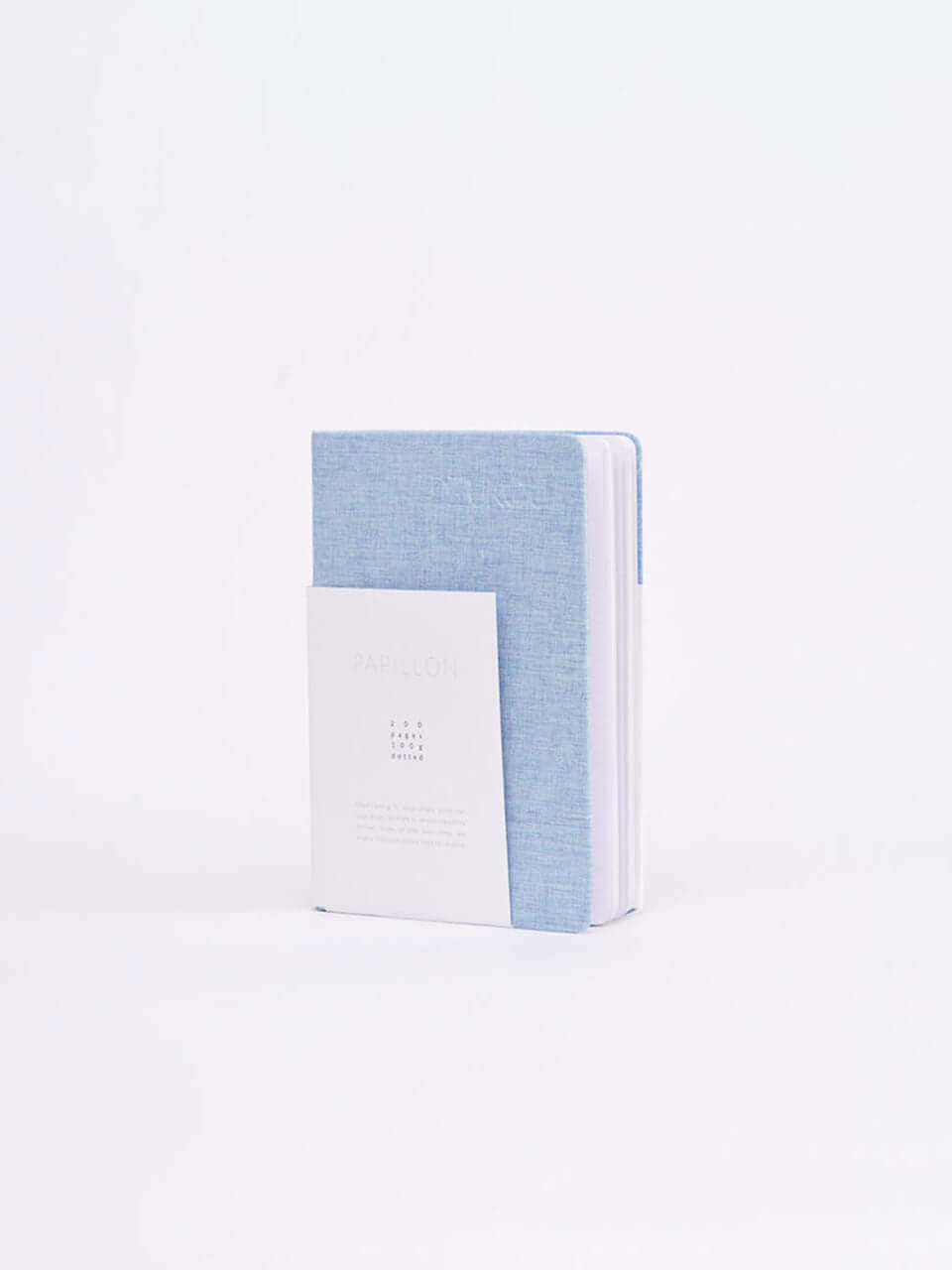 A linen notebook place beside a white block with a clean white background.