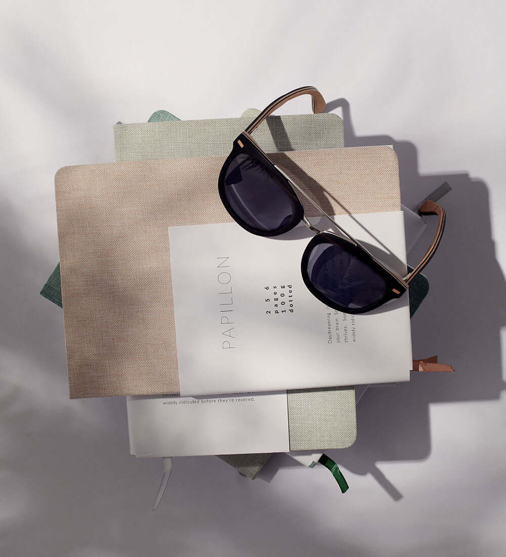 wooded sunglasses kept above a pile of books