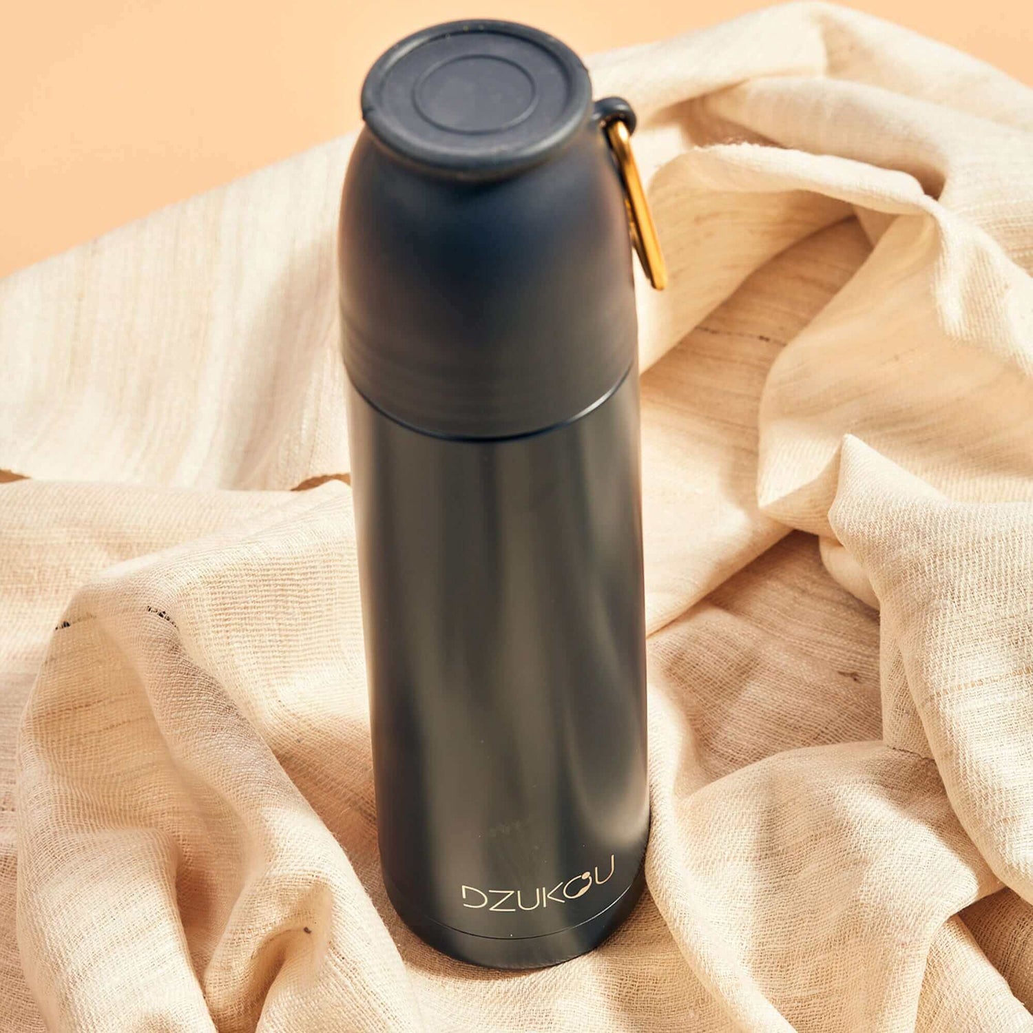 A black thermos flask placed on a textured cloth, showcasing its sleek design and functional elegance.