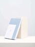 A linen notebook place beside a white block with a clean white background.
