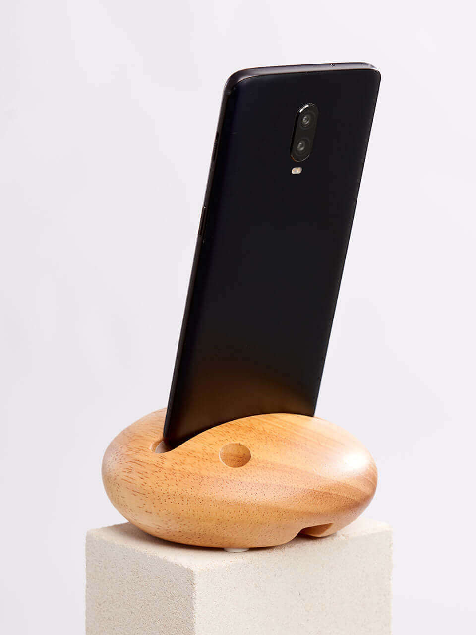 A cell phone placed on a white block, showcasing a blend of technology and natural materials.