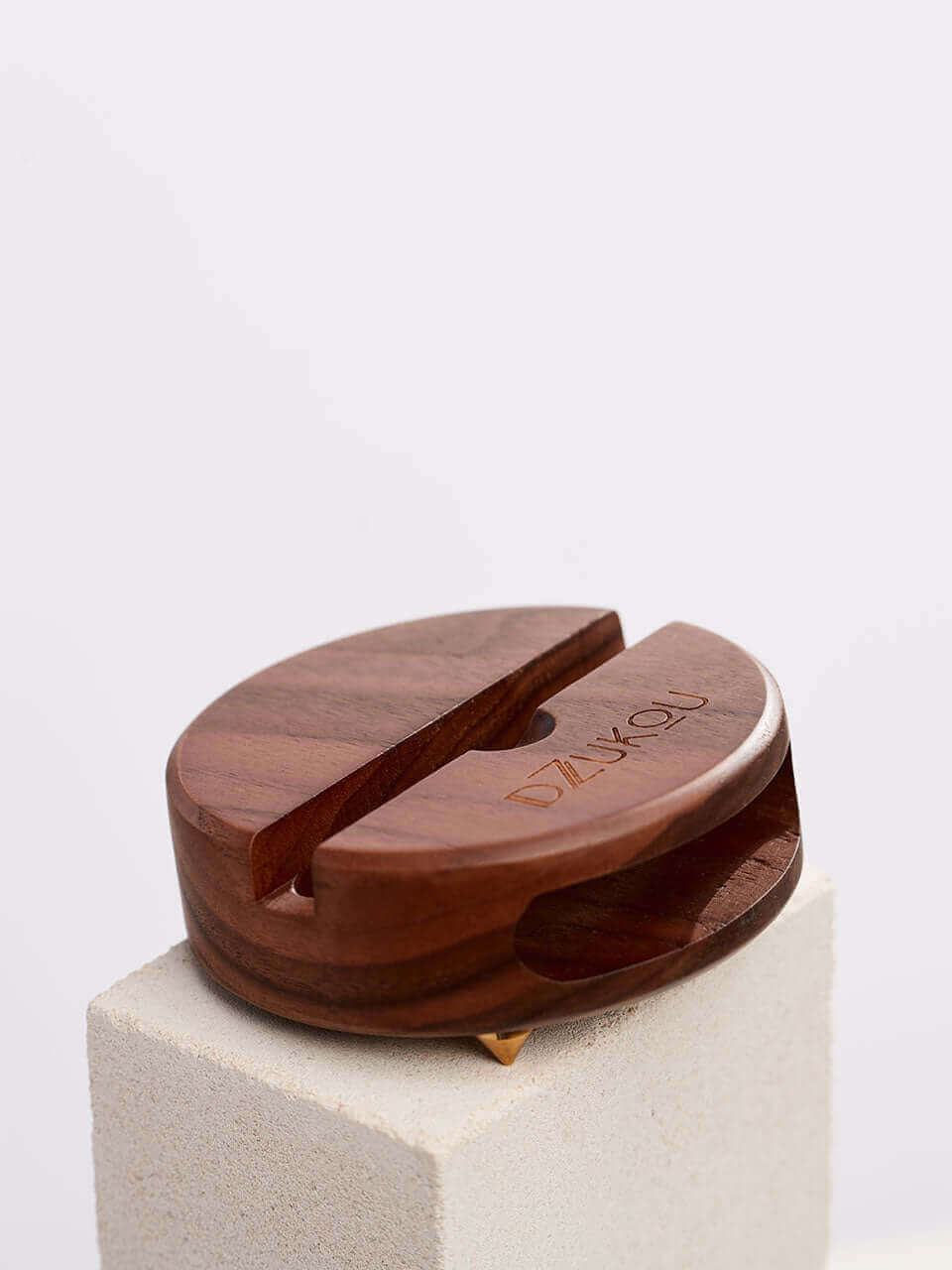 A cell phone stand placed on a white block, showcasing a blend of technology and natural materials.