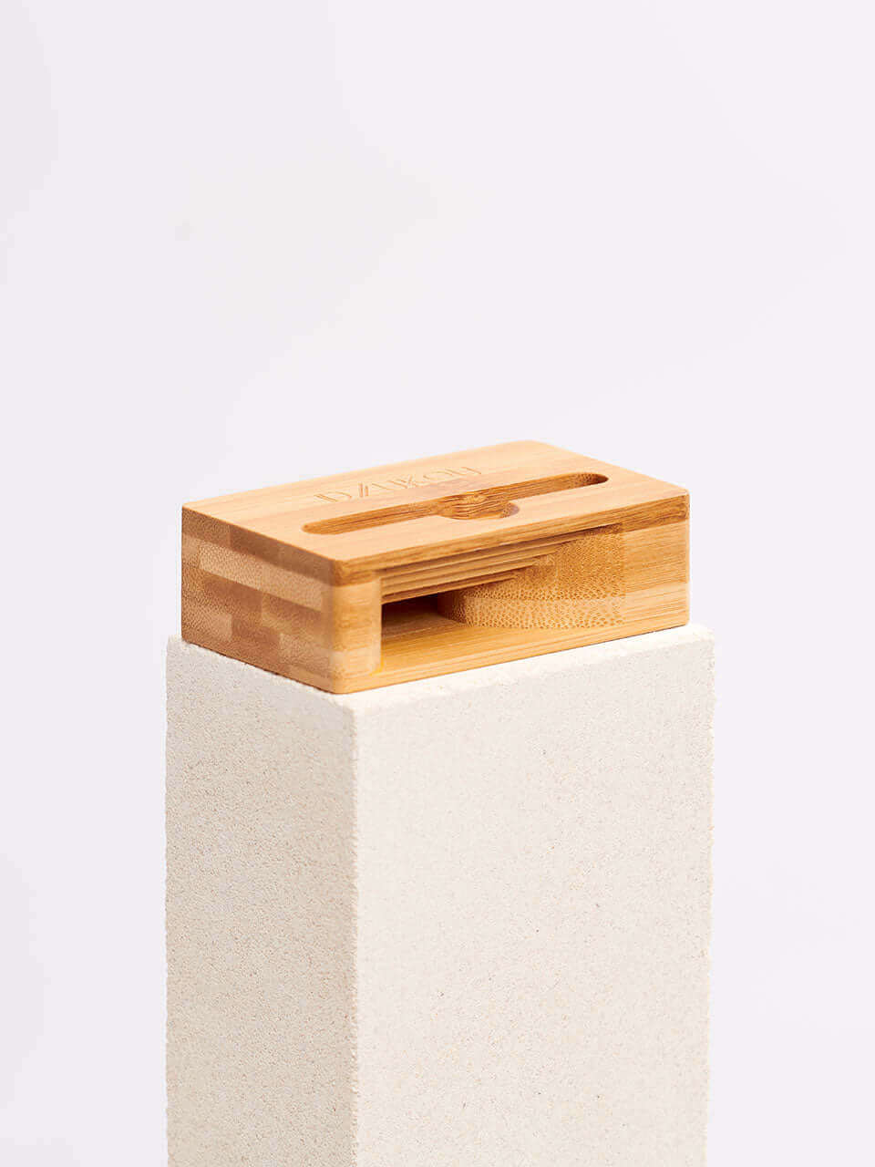 A cell phone stand placed on a white block, showcasing a blend of technology and natural materials.